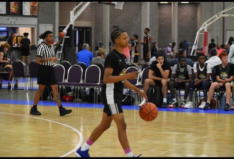 Young girl dribbling basketball during youth basketball game at indoor gym.